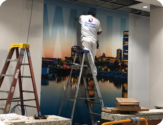 Man on ladder installing Milwaukee wallpaper